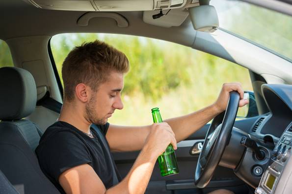 A person holding a bottle while driving

Description automatically generated